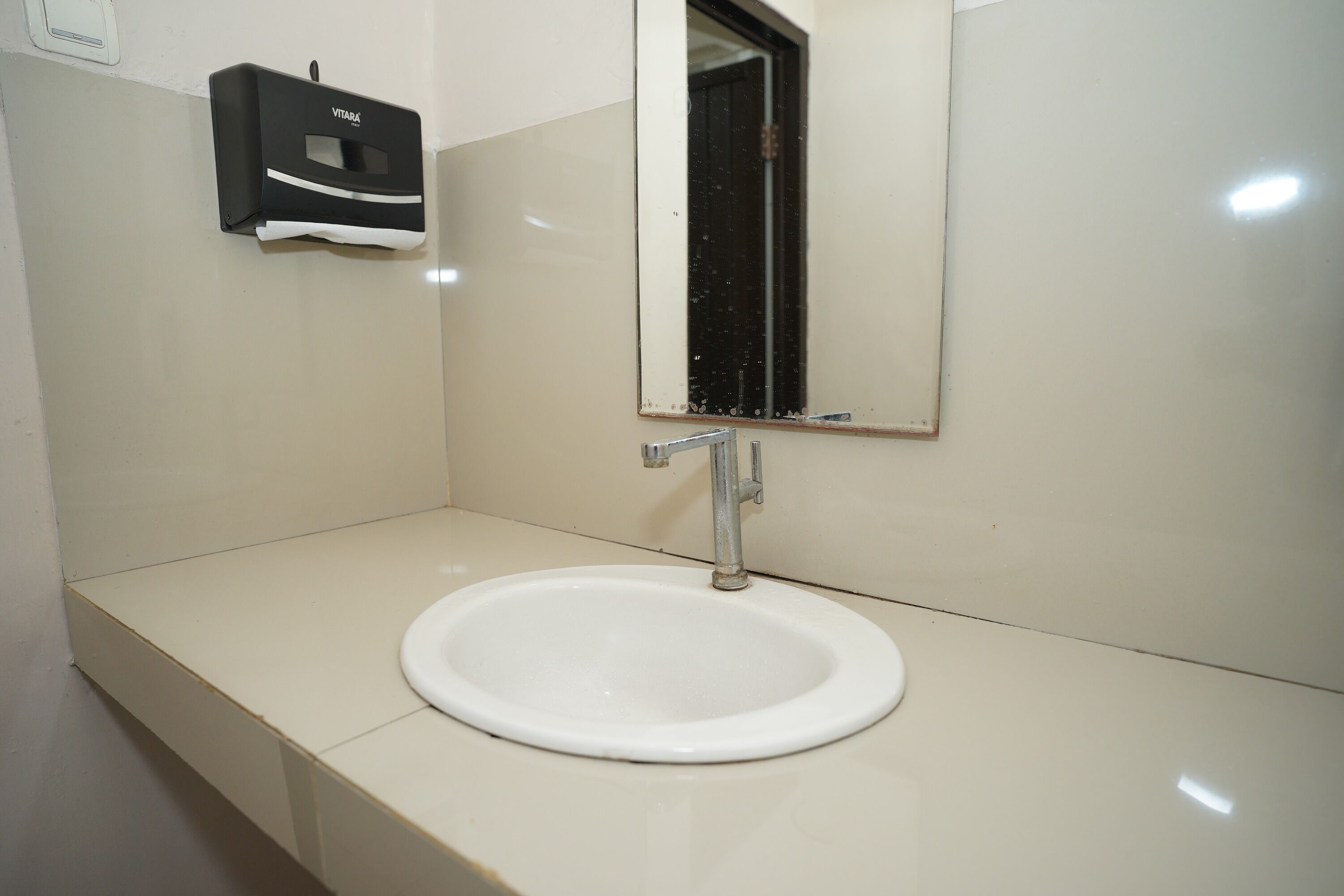 A bathroom with a white sink, a mirror, and a hand dryer.