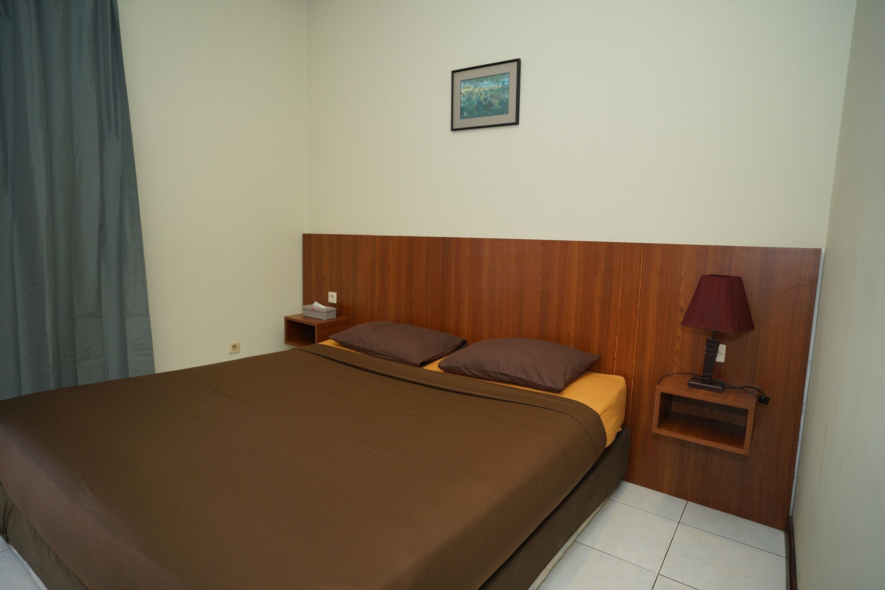 Une chambre d’hôtel avec un grand lit, une tête de lit en bois, une table de chevet avec une lampe et un tableau au mur.