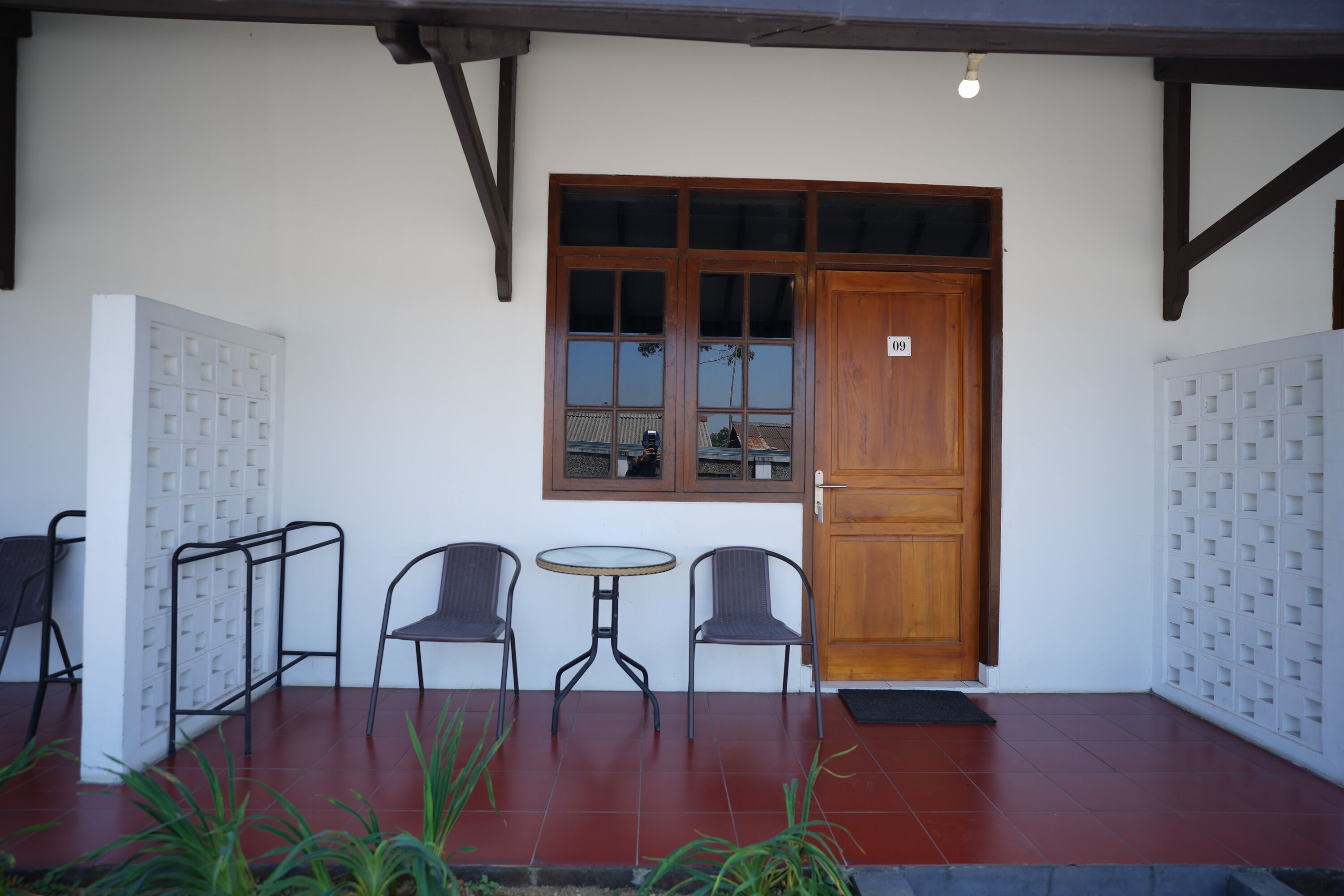 A building entrance with a wooden door, a window, and two chairs.