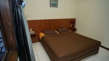 Un dormitorio con cabecera de madera, cama con ropa de cama marrón, mesita de noche con lámpara y un cuadro enmarcado en la pared.