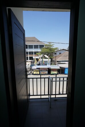 Uitzicht vanaf een balkon met een metalen hekwerk, een helderblauwe lucht en gebouwen op de achtergrond.