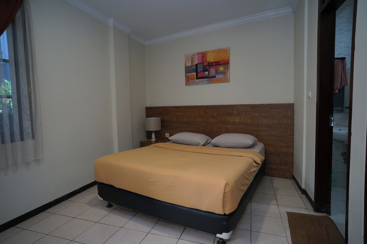 Ein Hotelzimmer mit einem Bett, einem Nachttisch, einer Lampe und einem Bild an der Wand.