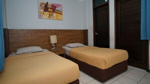 Una habitación de hotel con dos camas, un cabecero de madera, una mesita de noche, una lámpara y un cuadro en la pared.