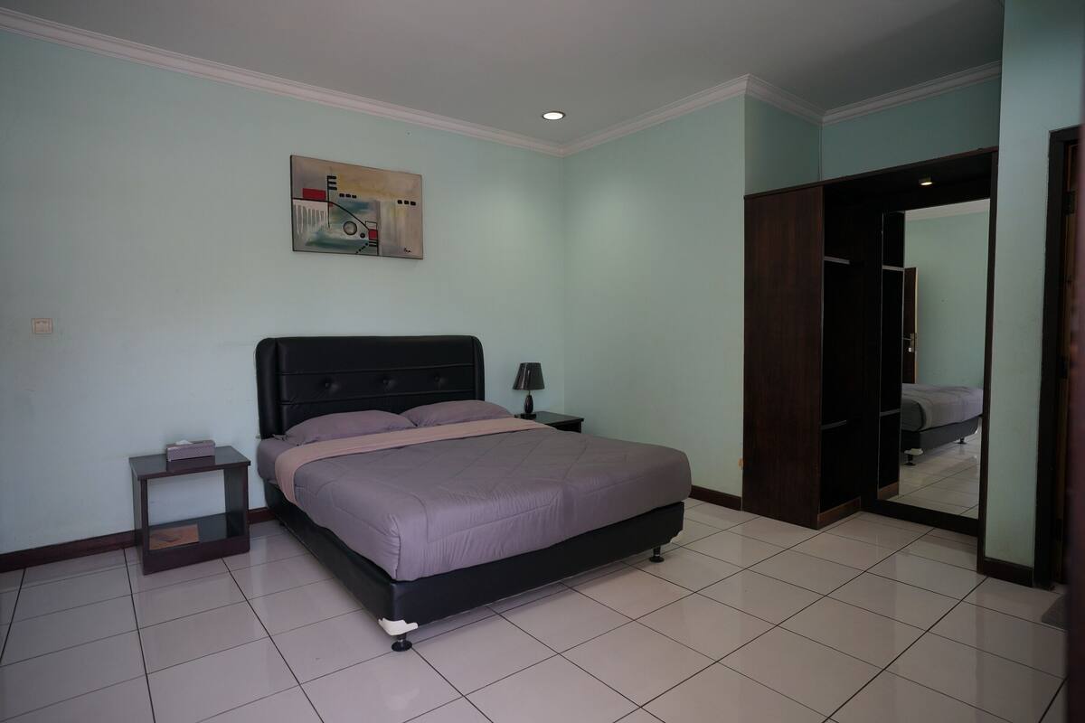 Un dormitorio con cama, mesita de noche y un cuadro en la pared.