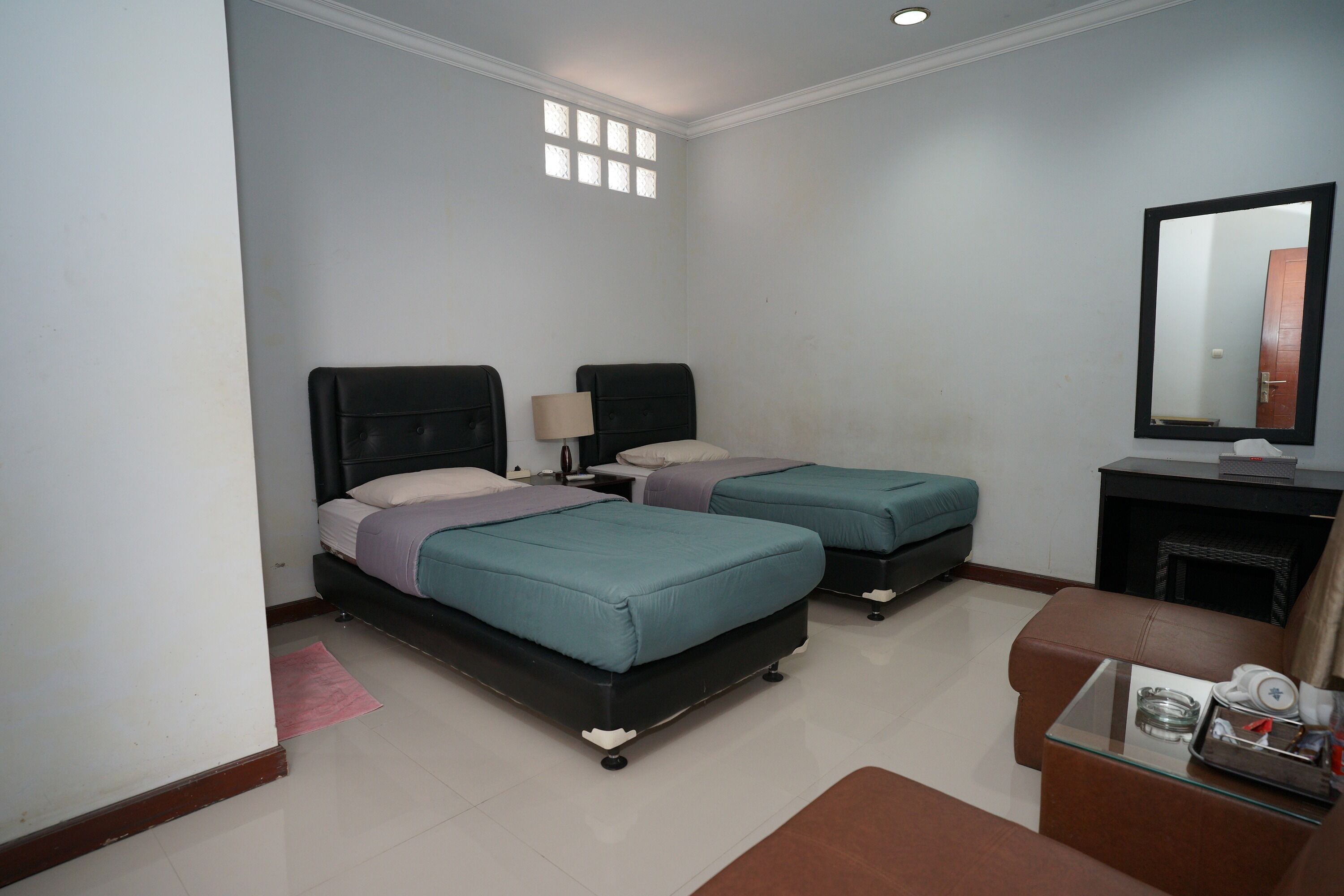 A hotel room with two beds, a small sofa, a TV, and a fireplace.