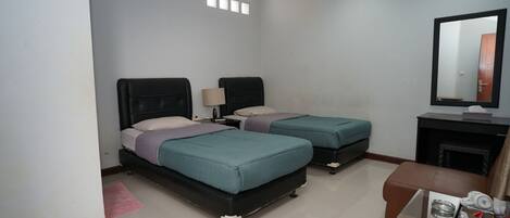 A hotel room with two beds, a small sofa, a TV, and a fireplace.