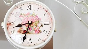 A wall-mounted clock with a floral design and Roman numerals. - Dragonfly B&B (Trapani)