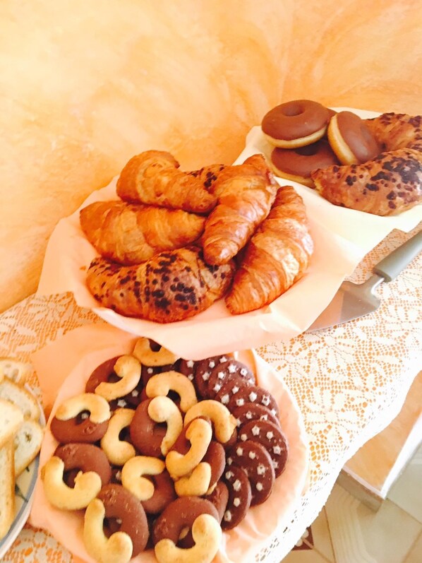 Uma mesa com doces, incluindo croissants e itens cobertos de chocolate.