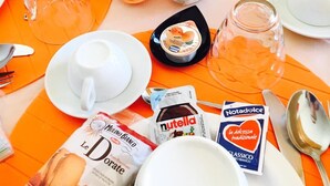 A breakfast table with various food items and condiments, including a carton of milk, a jar of jam, and a bottle of orange juice. - Dragonfly B&B (Trapani)