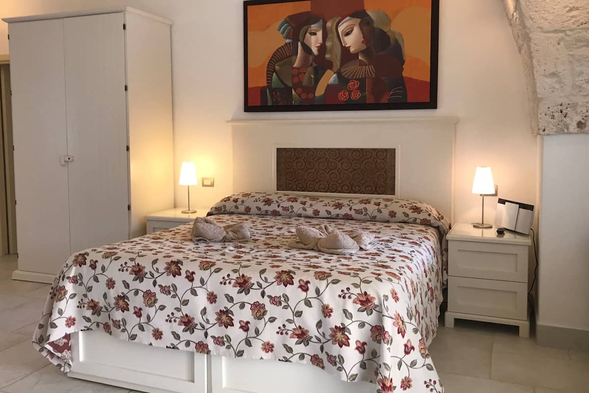 Ein Schlafzimmer mit einem Bett, zwei Nachttischen, einem Kleiderschrank und einem Bild an der Wand.