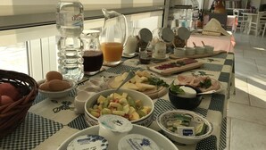A breakfast table with various food items, including fruits, cheeses, and beverages.