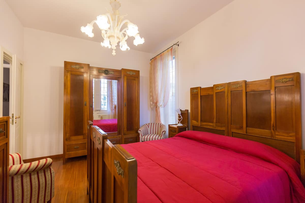 Ein Schlafzimmer mit einem hölzernen Bett, einem Sessel, einem Nachttisch und einer Chandelier.