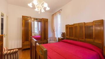 Ein Schlafzimmer mit einem hölzernen Bett, einem Sessel, einem Nachttisch und einer Chandelier.