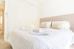 A hotel room with a neatly made bed, a bedside lamp, and a door with a light switch.