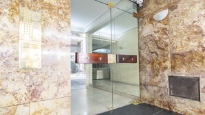 A modern lobby with marble walls, a glass partition, and a wooden elevator door.