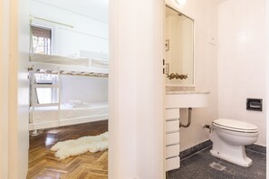 A room with a bunk bed, a white sink, a toilet, and a mirror.