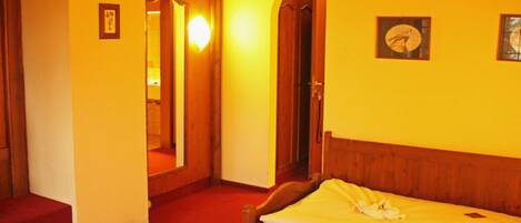 A hotel room with two wooden beds, a red carpet, and a mirror on the wall.