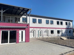 A two-story building with a flat roof, a covered entrance area, and a paved walkway leading to the entrance. - Hotel Haus Krone (Bexbach)