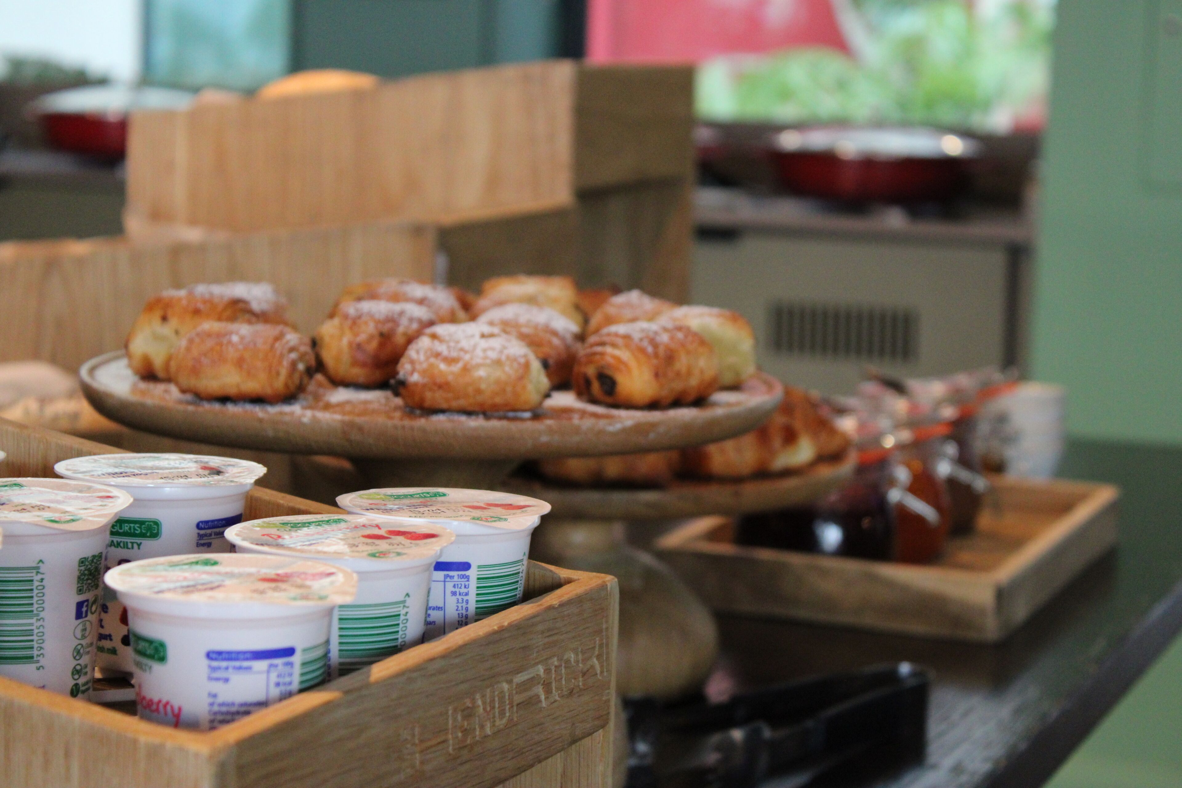 A breakfast buffet with pastries and yogurt containers.