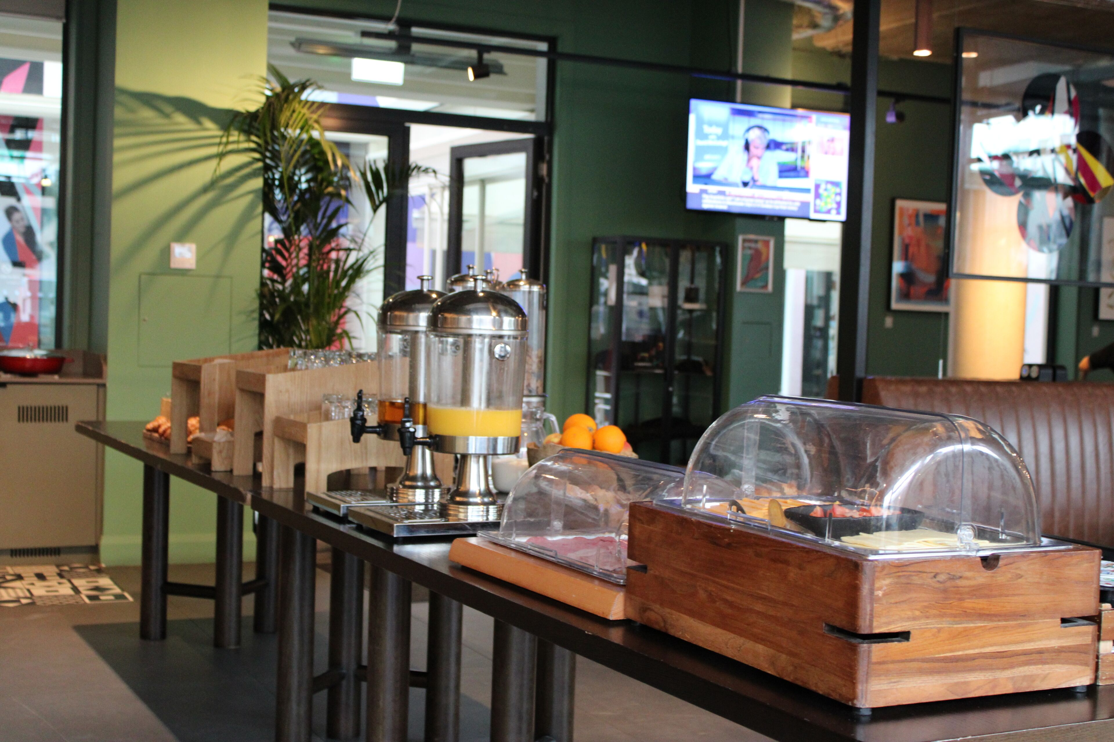 A breakfast bar with coffee machines, a TV, and a plant.
