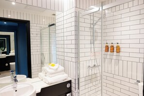 Habitación estándar | Baño | Ducha, artículos de higiene personal de diseño y secador de pelo