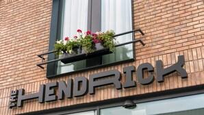 Un edificio con un letrero que dice "HENDRICK" y una ventana con un macetero de flores.