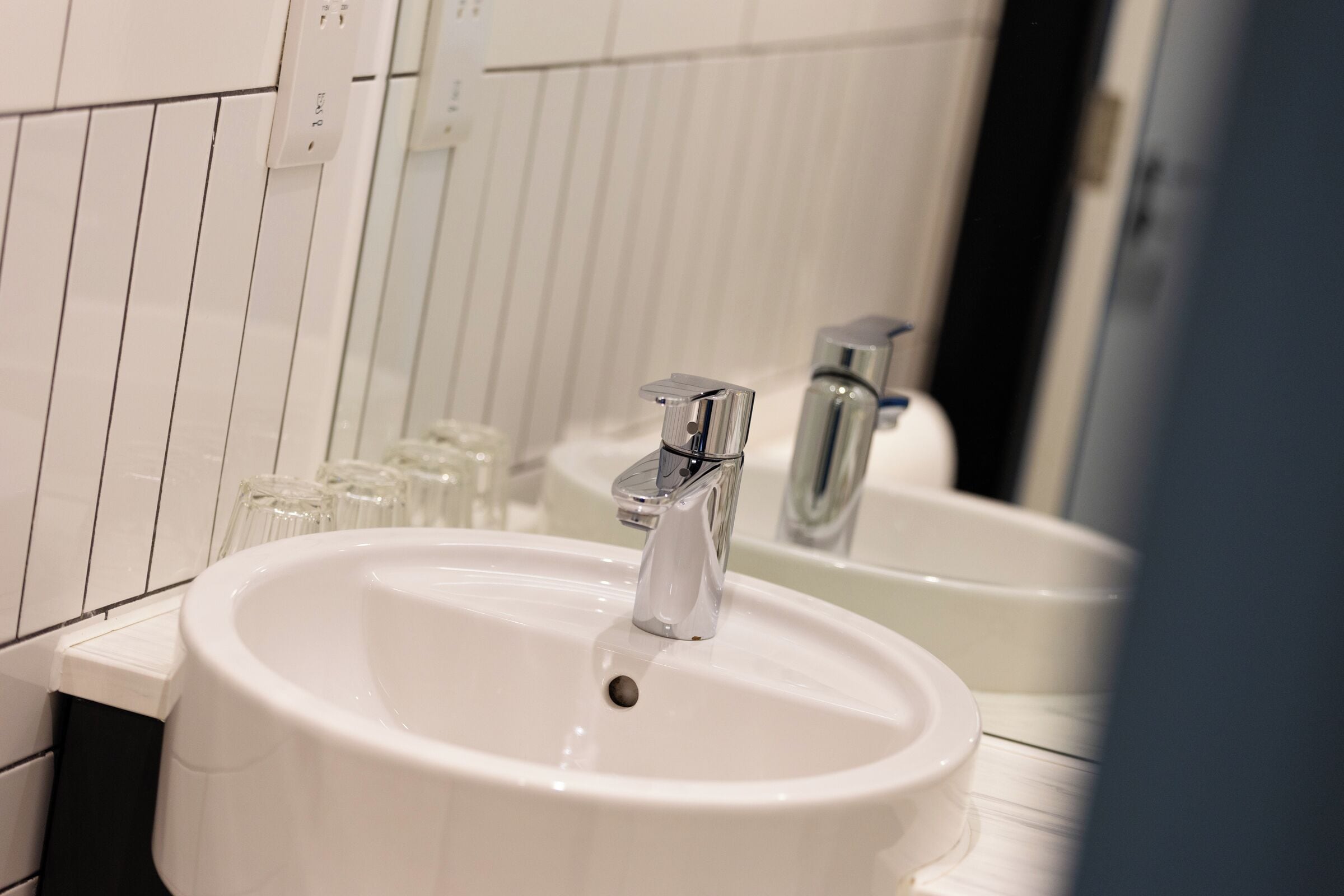A bathroom with a white sink, a mirror, and a faucet.