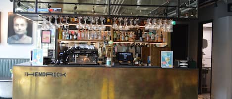 A bar area with a counter labeled "THE HENDRICK," stocked with various bottles and glasses.