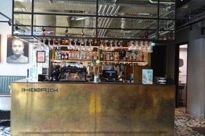 A bar area with a counter labeled "THE HENDRICK," stocked with various bottles and glasses.