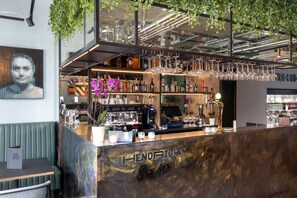 A bar area with a counter, shelves of bottles, and hanging glasses. - The Hendrick Smithfield (Dublin)