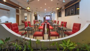 A conference room with red chairs and tables, ceiling fans, and potted plants. - Paguro Villa (Ukulhas)