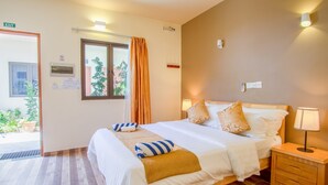 A hotel room with a bed, bedside table, lamp, and a window with curtains. - Paguro Villa (Ukulhas)