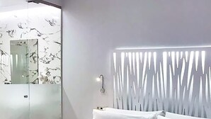 Ein modernes Schlafzimmer mit einem großen Bett, einer Duschkabine aus Glas und einem außergewöhnlichen Wandpaneel-Design.