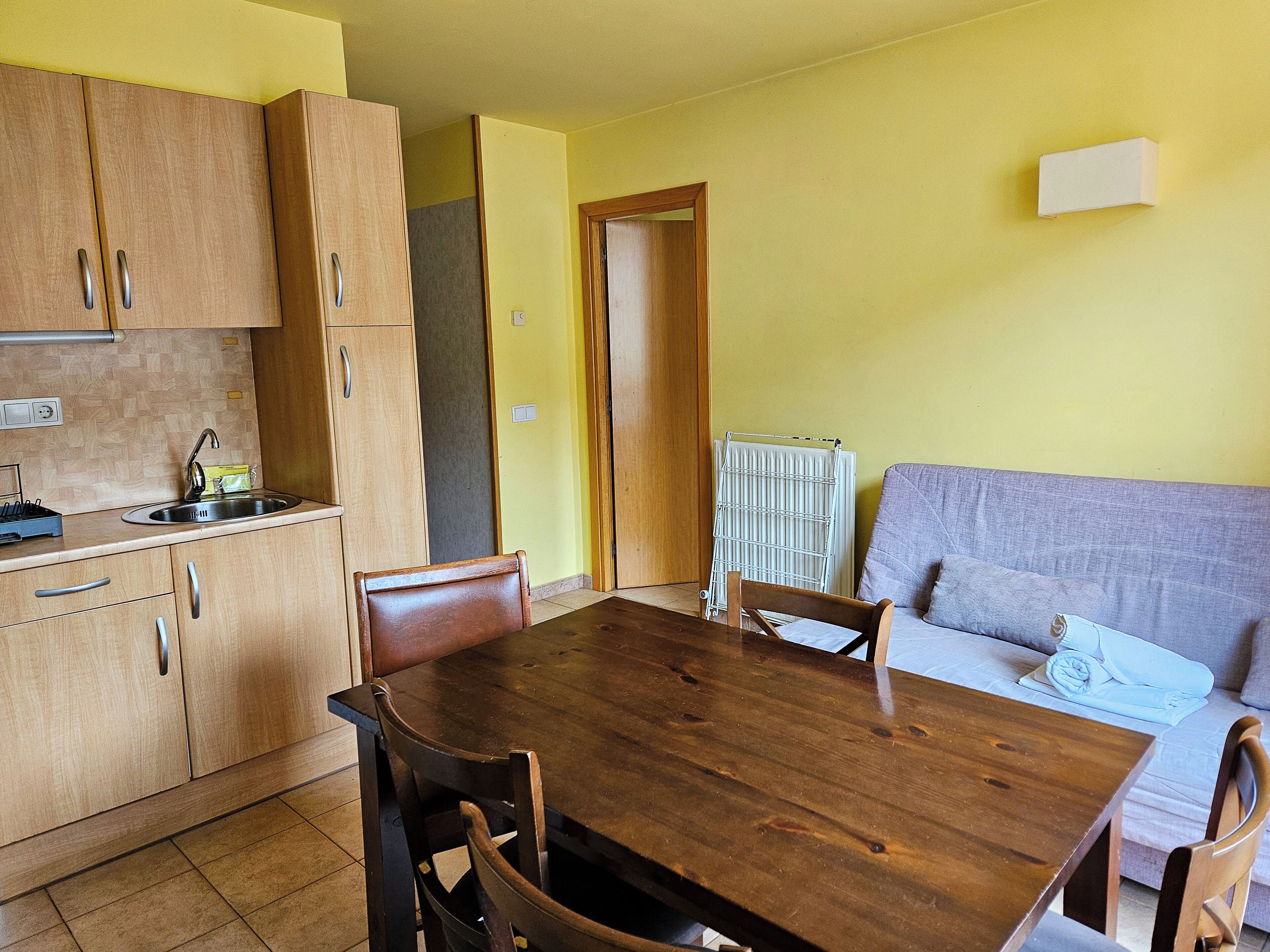A compact kitchen with wooden cabinets and a dining table.
