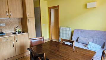 A compact kitchen with wooden cabinets and a dining table.