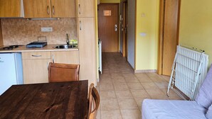 A compact kitchen with wooden cabinets, a dining table, and a radiator. - Apartamentos Canillo Ribagrossa 3000 (Canillo)