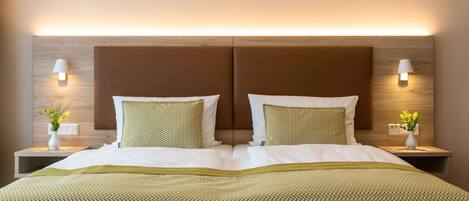 Habitación de hotel con una cama grande, dos mesitas de noche y lámparas de pared.