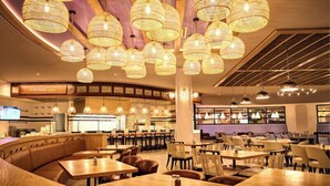 A restaurant with multiple seating areas, including booths and tables, and a bar area in the background. - Wind Creek Casino & Hotel Atmore (Atmore)