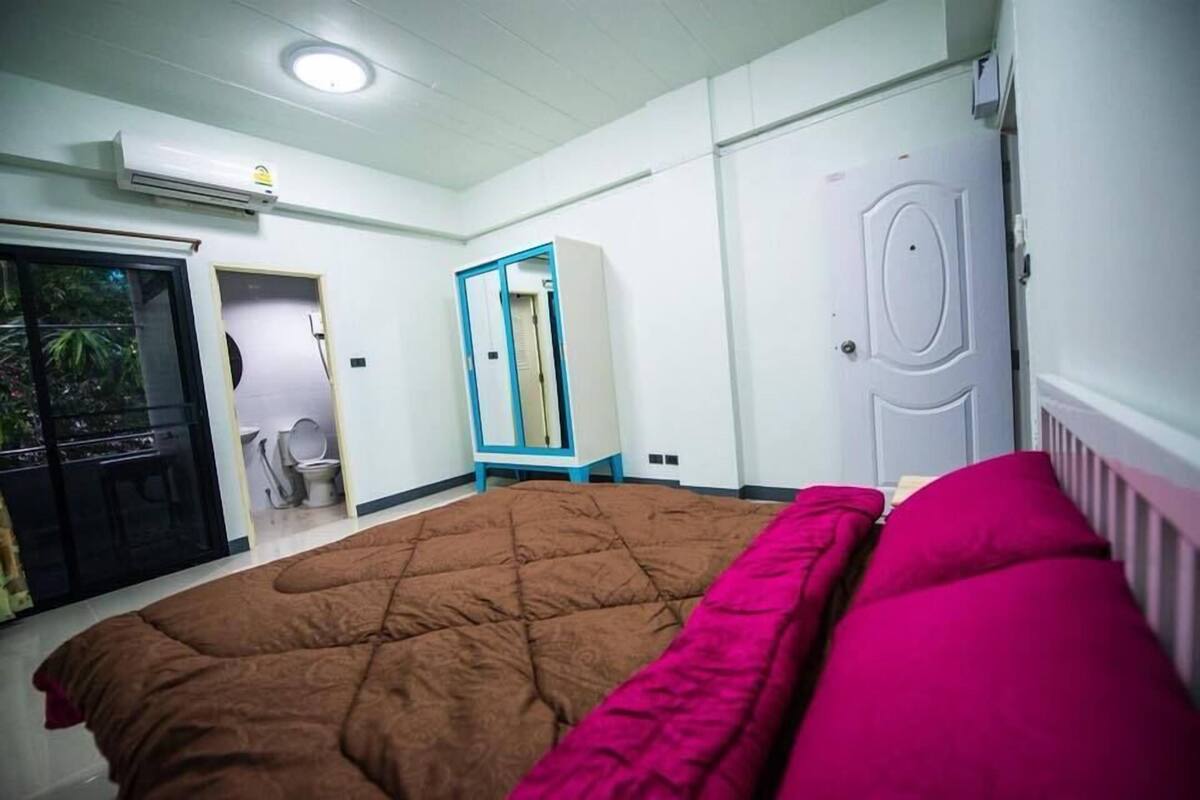 Een slaapkamer met een bed, een kledingkast, een deur en een airconditioner.