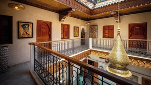 A multi-level atrium with ornate railings, a central chandelier, and artwork on the walls. - Riad Atlas Acacia (Marrakech)