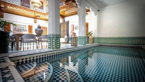 A pool with geometric tile patterns, a seating area, and a balcony with ornate railings. - Riad Atlas Acacia (Marrakech)