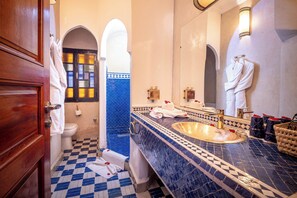 A bathroom with a checkered floor, a sink with a gold basin, and a mirror with a towel hanging on it. - Riad Atlas Acacia (Marrakech)