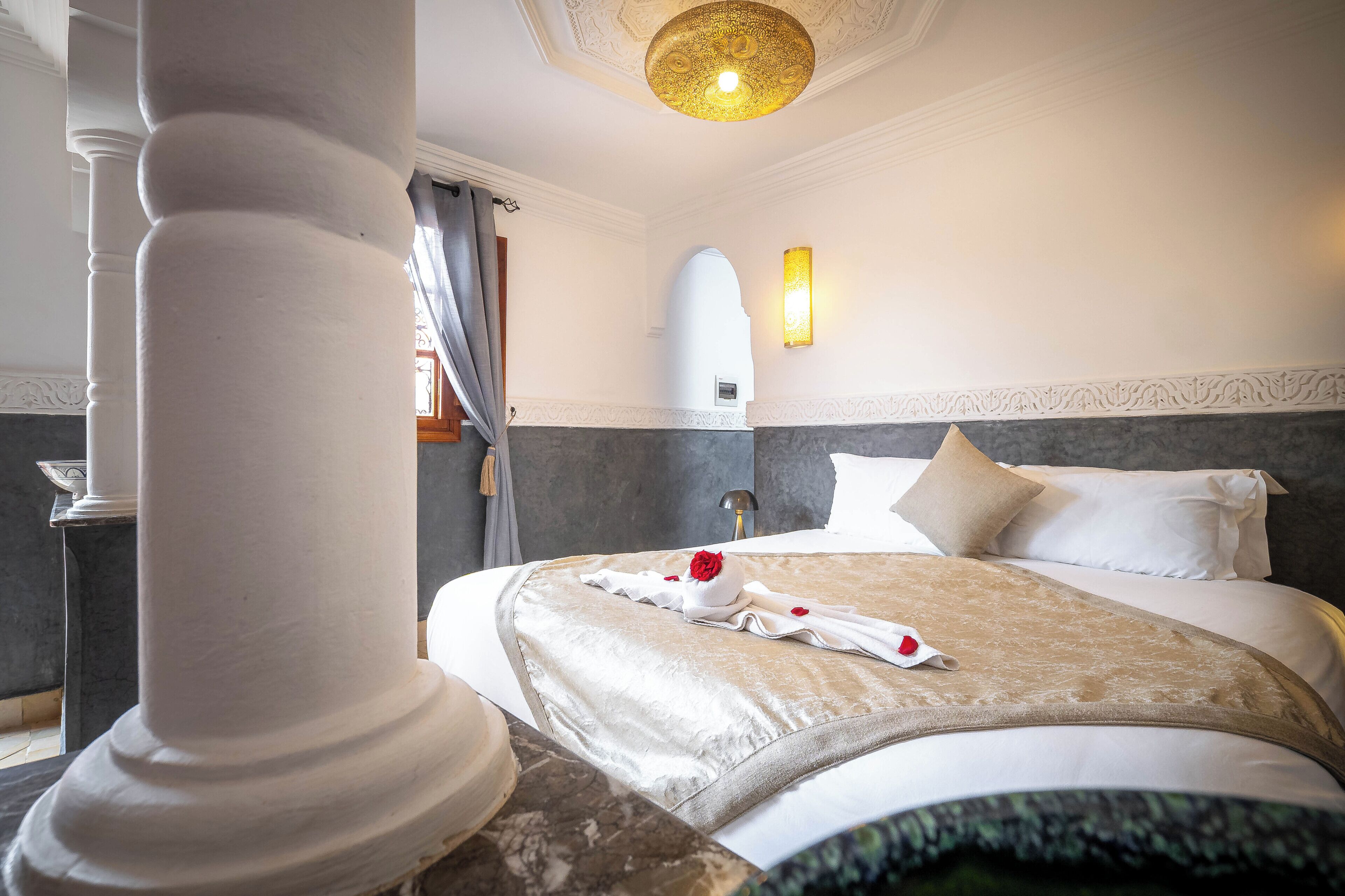 Una habitación de hotel con una cama grande, un techo decorativo y una lámpara fijada a la pared.