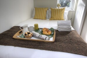 A neatly made bed with a brown blanket, a tray with breakfast items, and a window with a view of trees. - R2 Medium Studio (London)