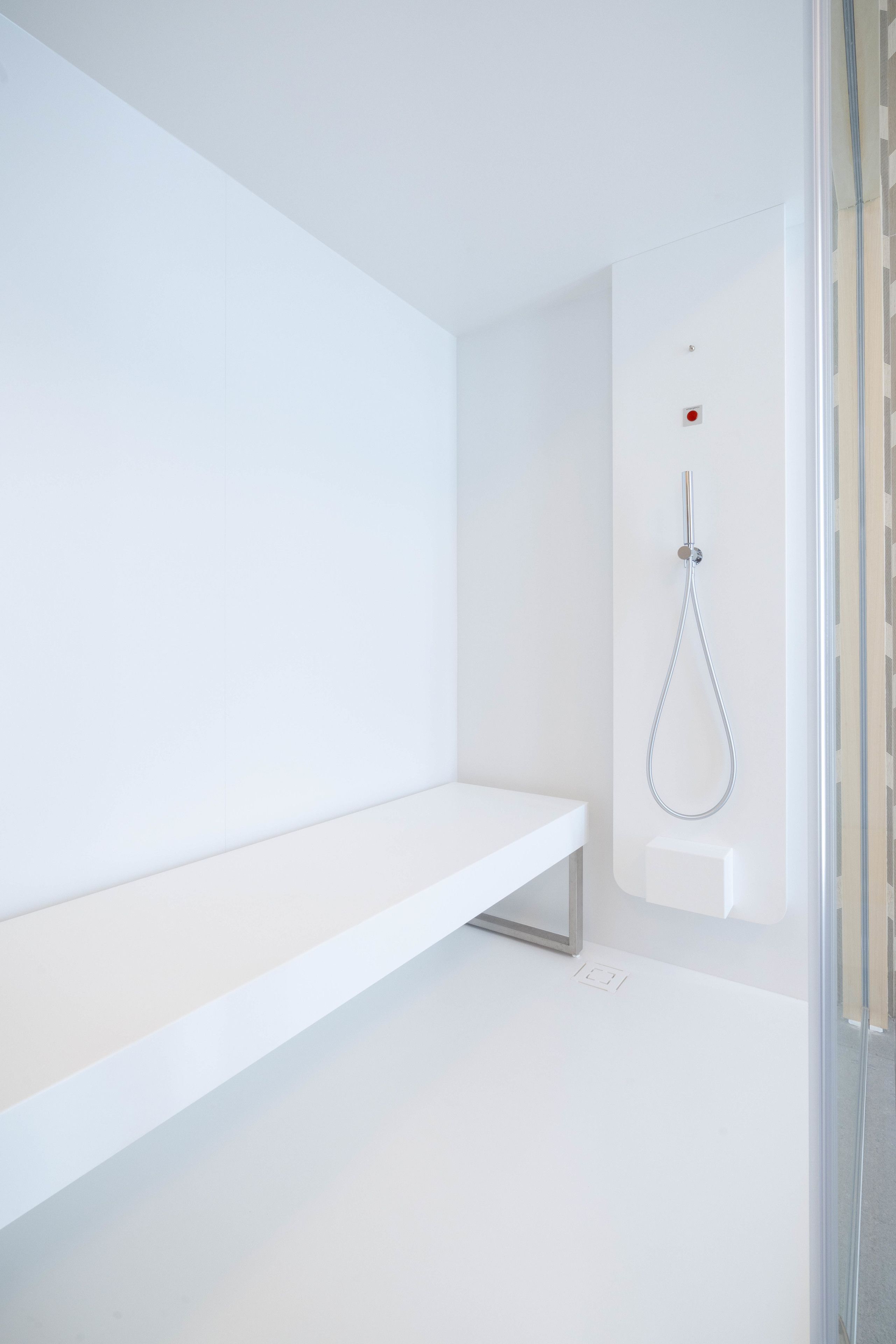 Casa de banho moderna com lavatório branco, chuveiro com chuveiro manual e cabine de duche em vidro.