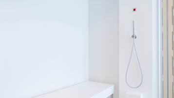 Casa de banho moderna com lavatório branco, chuveiro com chuveiro manual e cabine de duche em vidro.