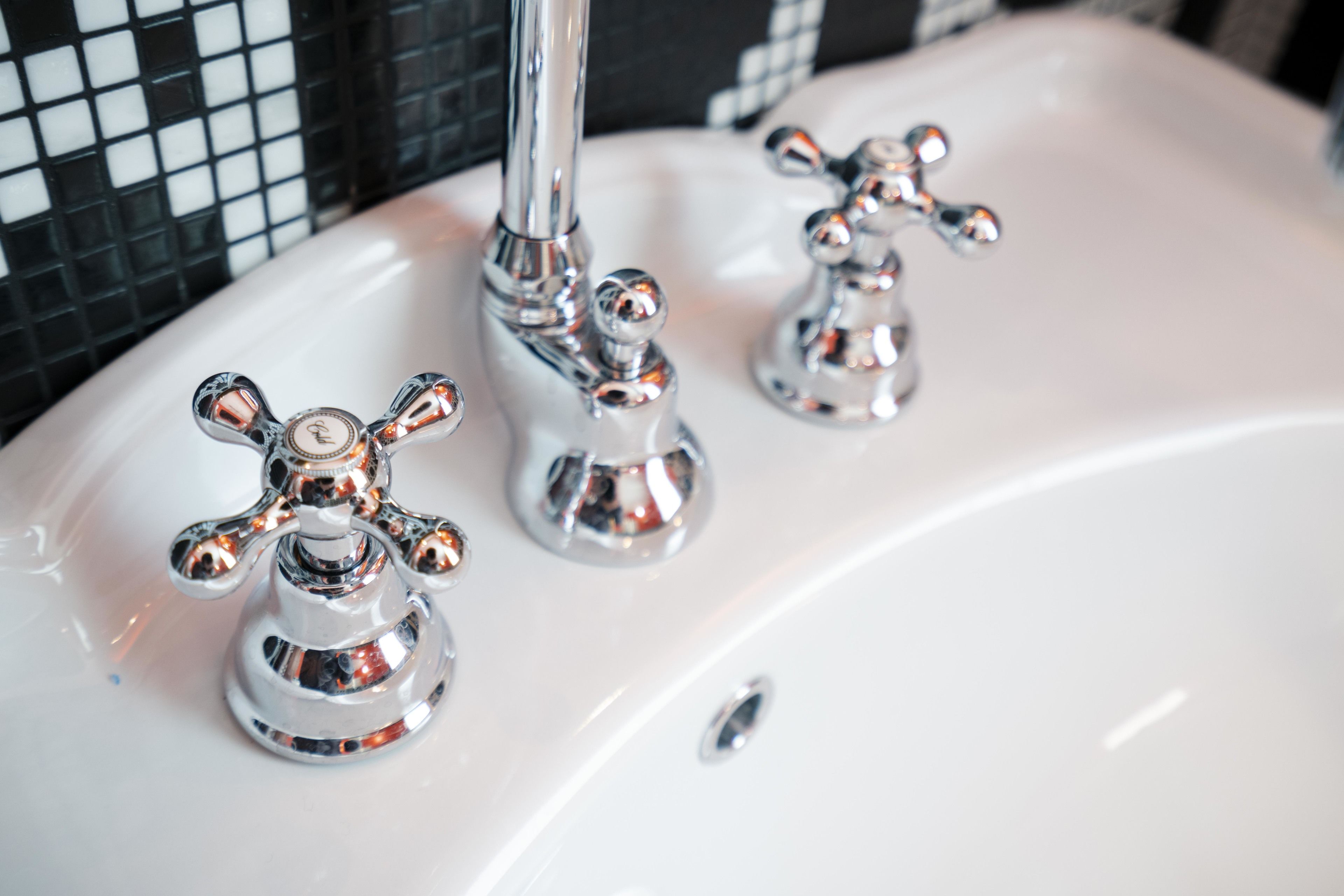 A white sink with three chrome faucets.