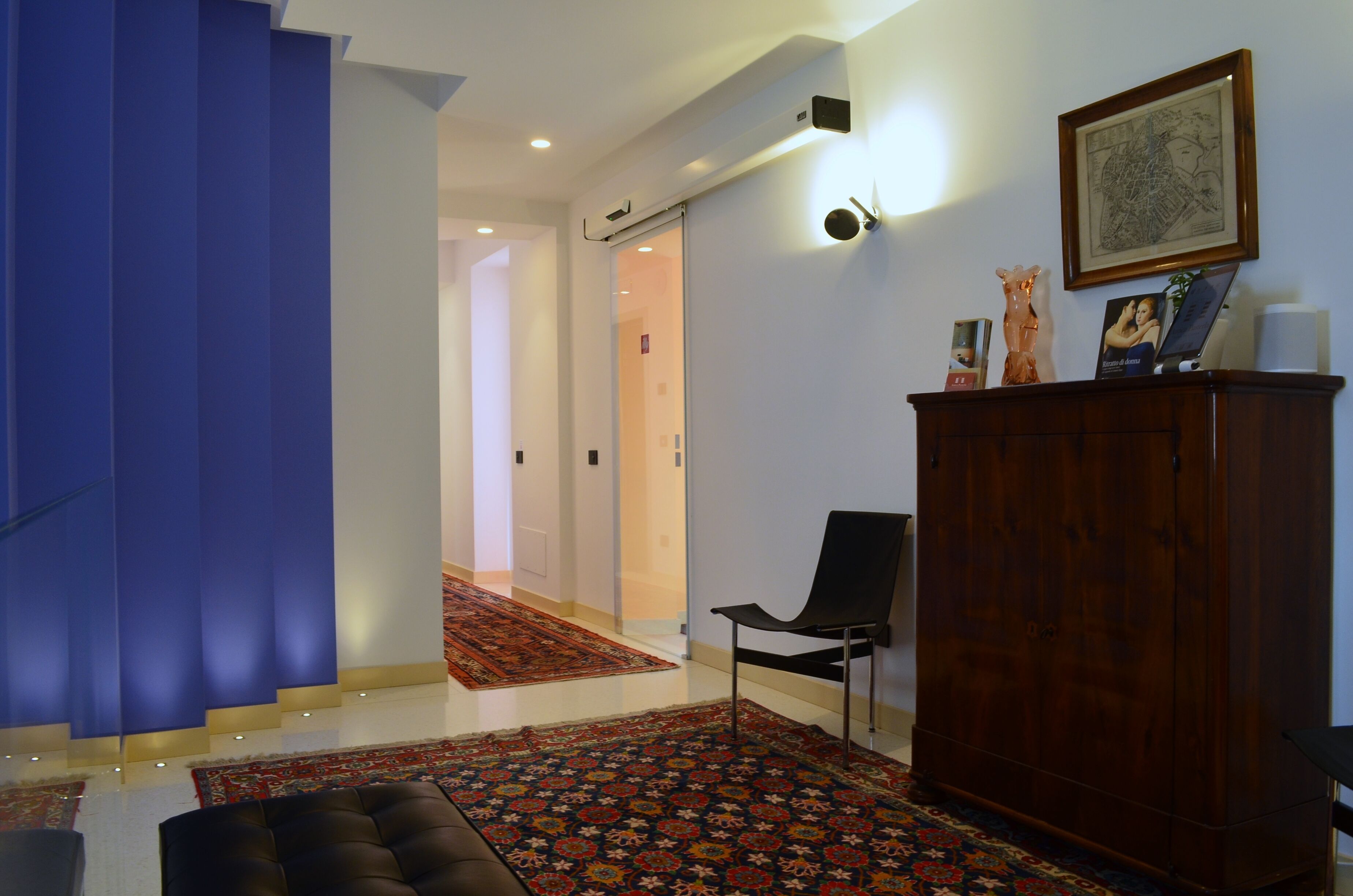 A modern living room with a staircase, a wooden cabinet, and a patterned rug.