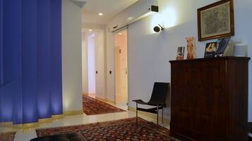 A modern living room with a staircase, a wooden cabinet, and a patterned rug.