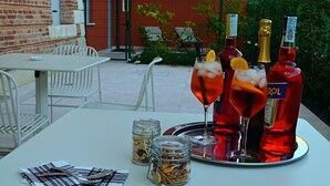 Mesa al aire libre con dos botellas de licor rojo, dos vasos con hielo y adornos, y dos recipientes de nueces sobre una bandeja.